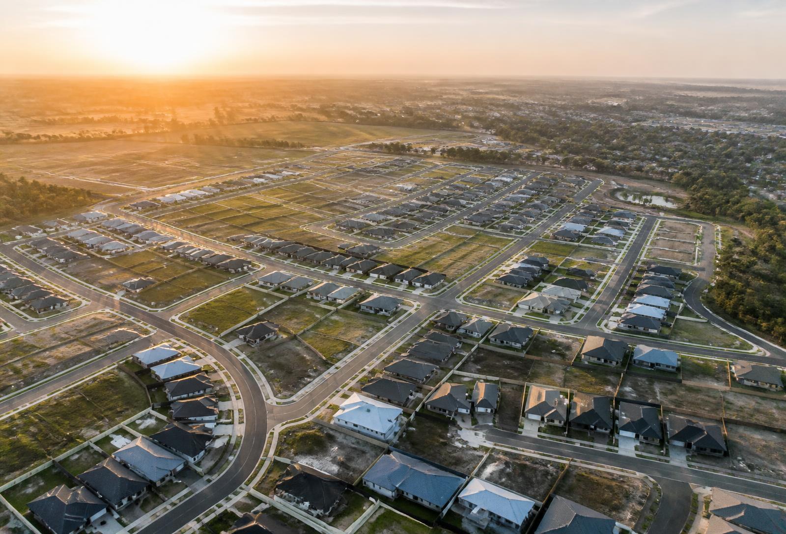 Aerial view of a new master planned housing estate with vacant allotments at sunrise